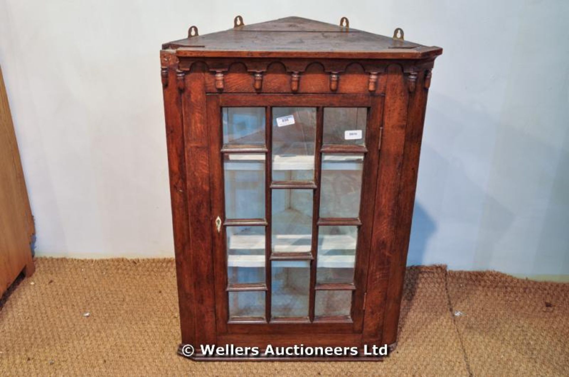 A small Georgian oak hanging corner cabinet, ivory escutcheon to hinged glazed door opening to