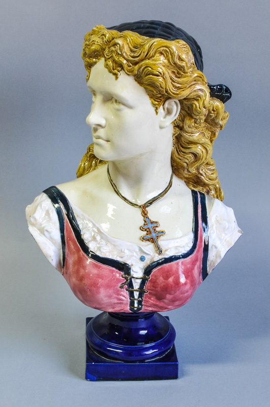 A large French Majolica bust of a girl, with head turned to one side, with cross of Lorraine