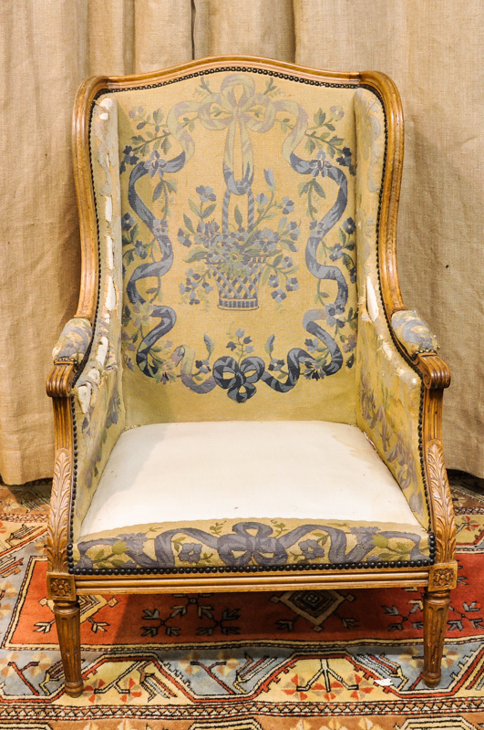 A French wing armchair, stiff leaves to arms on reeded legs, 106cm high