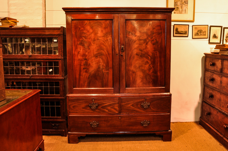 A George III mahogany linen press, converted to a wardrobe, with two panelled doors enclosing