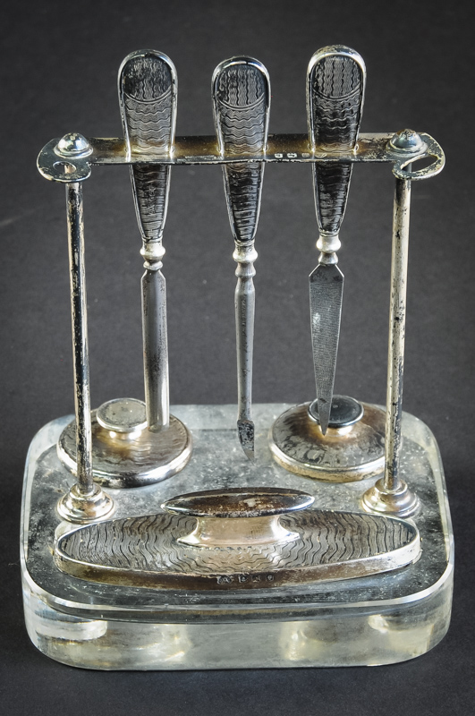 An Art Deco manicure set, stand mounted on glass base, Birmingham 1930, by Adie Bros, for retailer