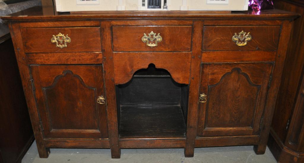 An oak low dresser, plain top over three drawers with dog kennel below flanked by cupboards, 84 x