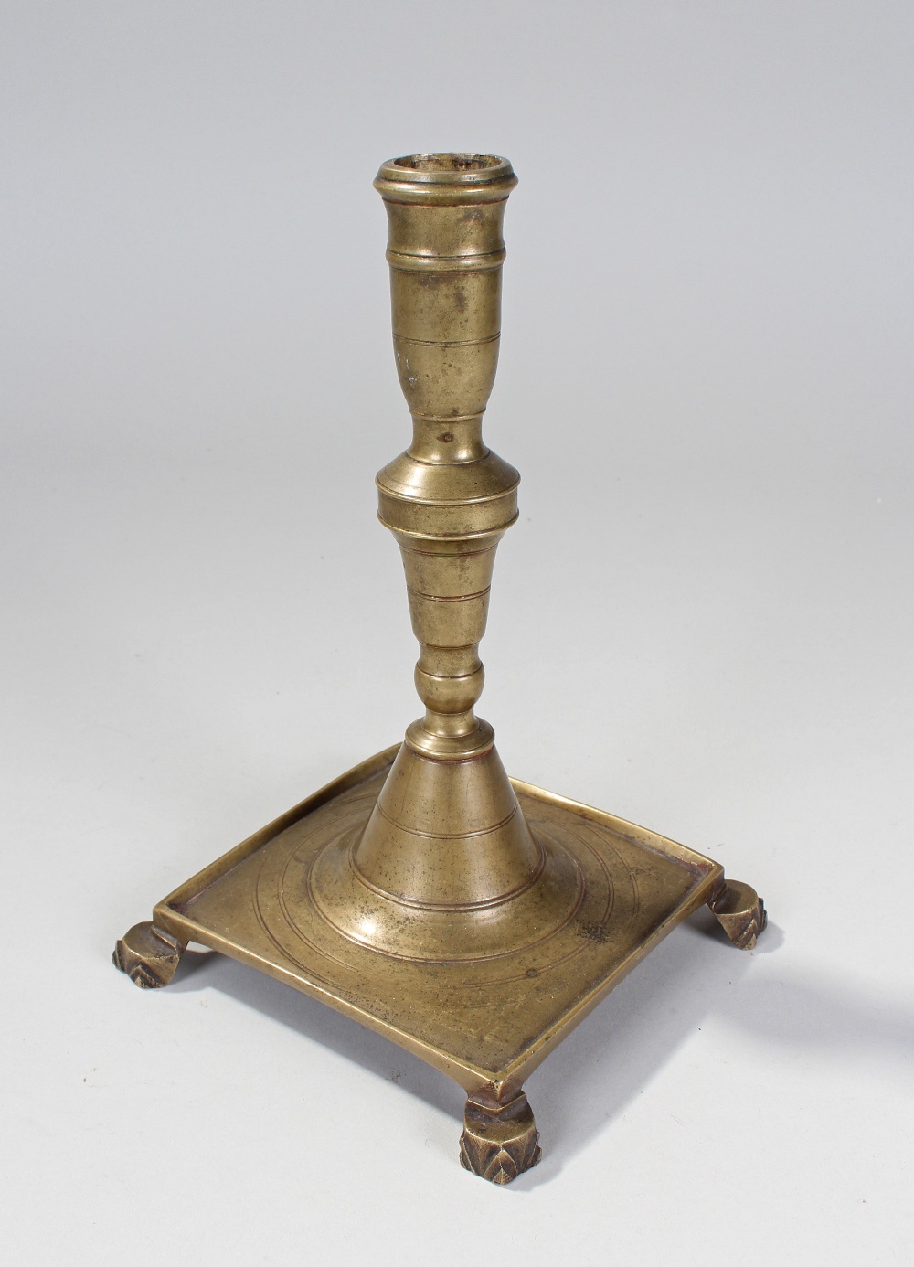 18th Century brass candlestick, having ring turned cylindrical nozzle, knopped column with square