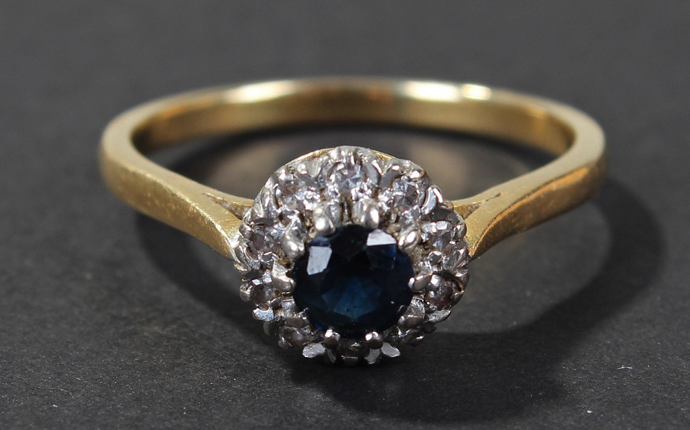 18 carat gold diamond blue sapphire set ring, centered with single blue sapphire, surrounded by