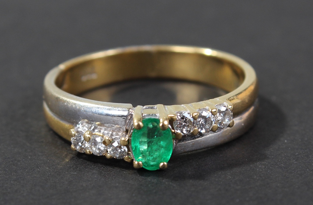 18 carat gold emerald and diamond set ring, set with single oval cut emerald flanked by a row of