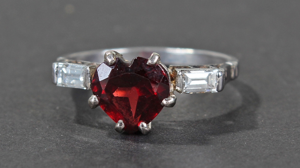 Platinum diamond and ruby ring, with central heart shape ruby, flanked with a pair of baguette cut