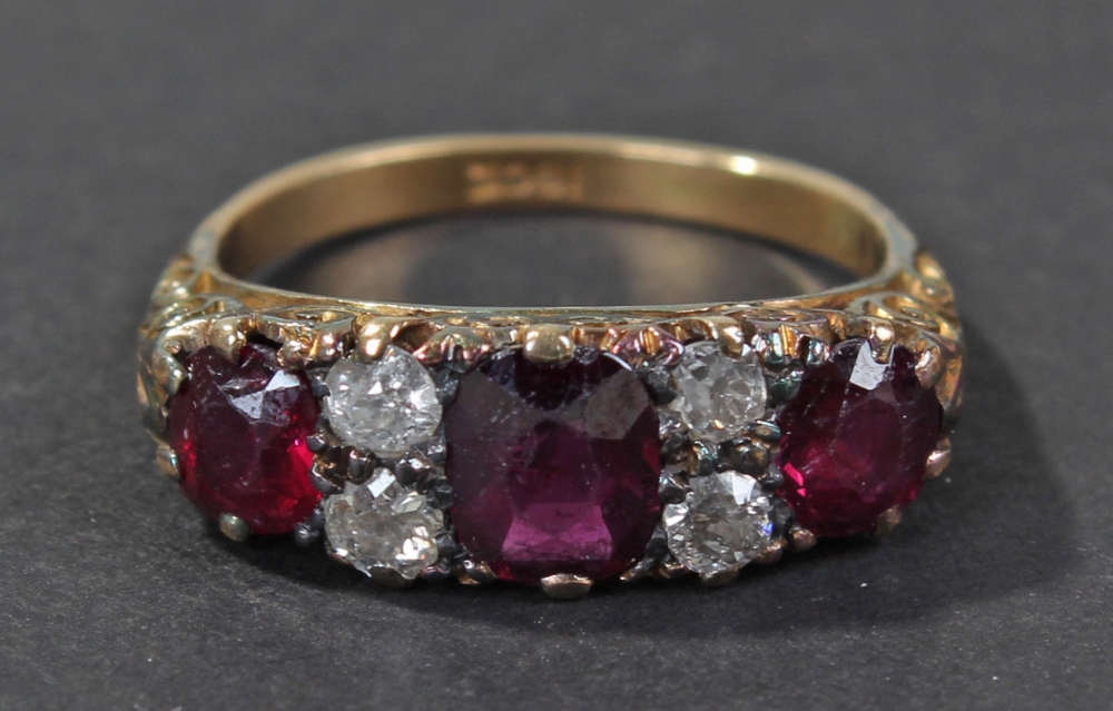 18 carat gold diamond and ruby set ring, the scrolling pierced head set with three graduating rubies