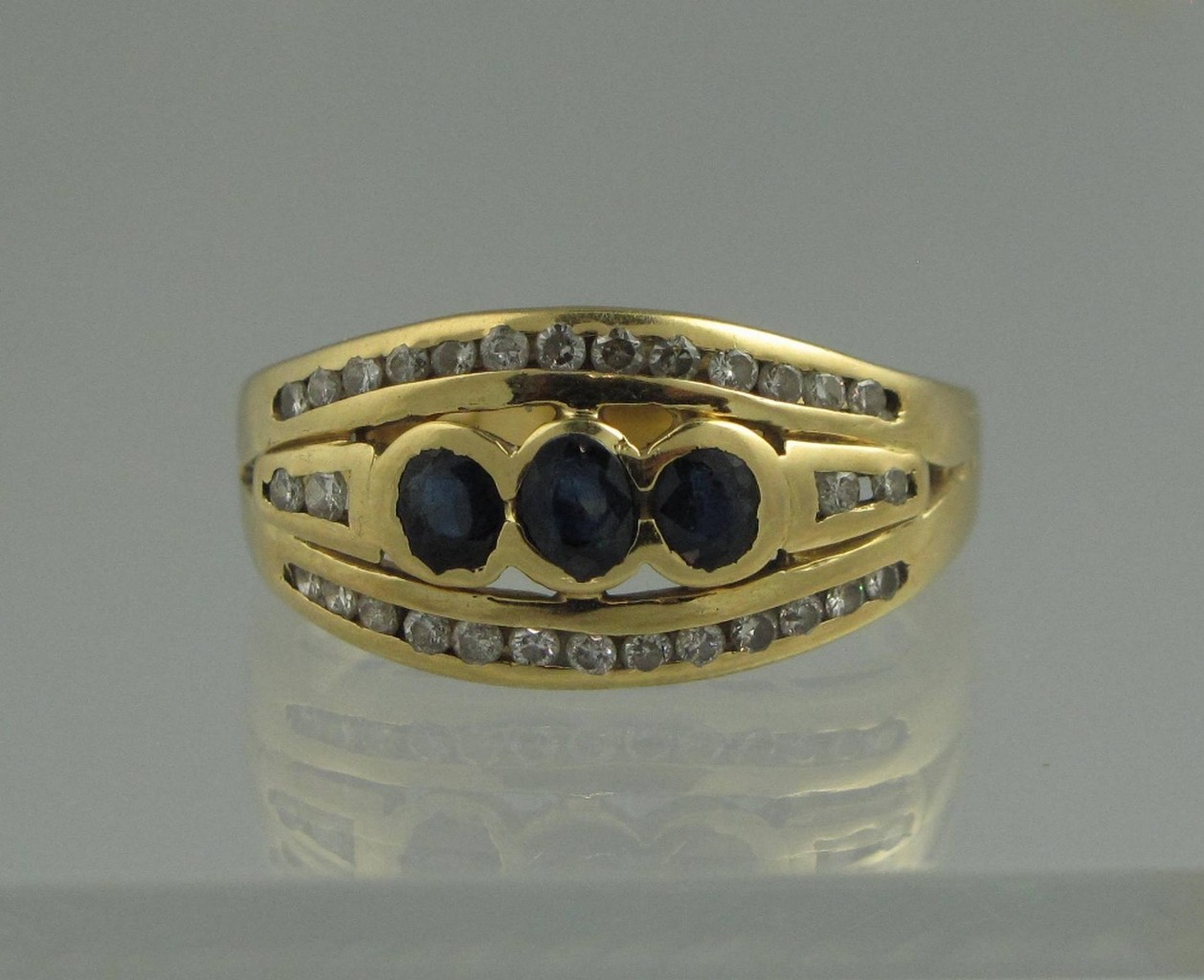 AN 18CT GOLD SAPPHIRE AND DIAMOND RING. The three central sapphires set with a row of diamonds