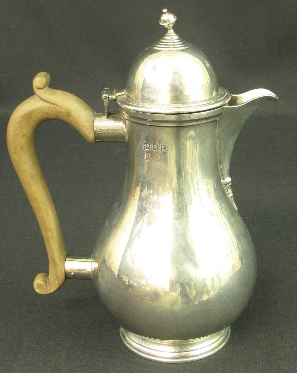 A GEORGE V SILVER HOT WATER JUG, of baluster form having high domed hinged cover and wooden