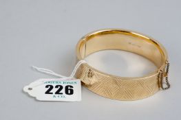 A nine carat gold wide bright cut hollow bangle, 28 grms