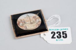 An oblong rose gold framed brooch having an oval micro mosaic scene of Rome with a black jet