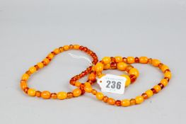 A necklace of graduated amber coloured beads alternating between solid cloudy beads and faceted