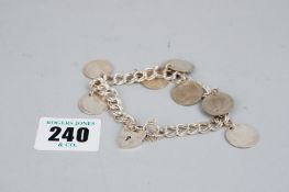 An unmarked white metal, believed silver, double strand link coin bracelet with silver padlock and