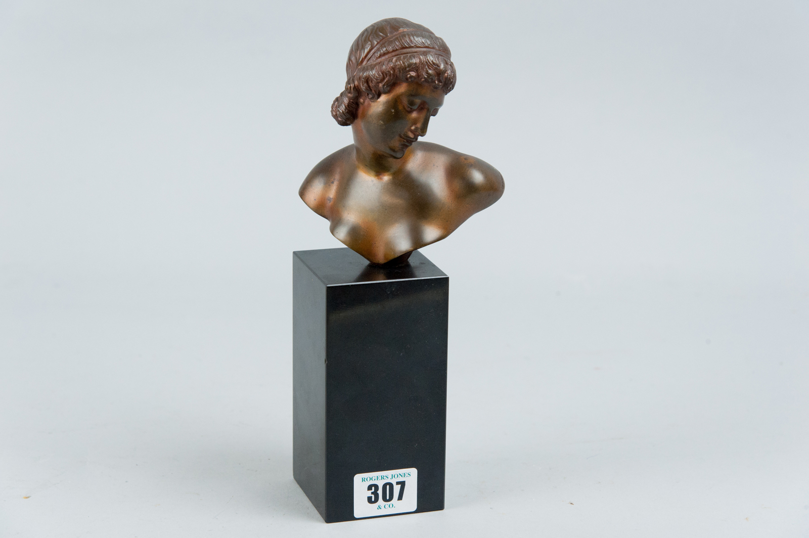 A small bronze bust set upon a black granite plinth of a classical young maiden, marks impressed to
