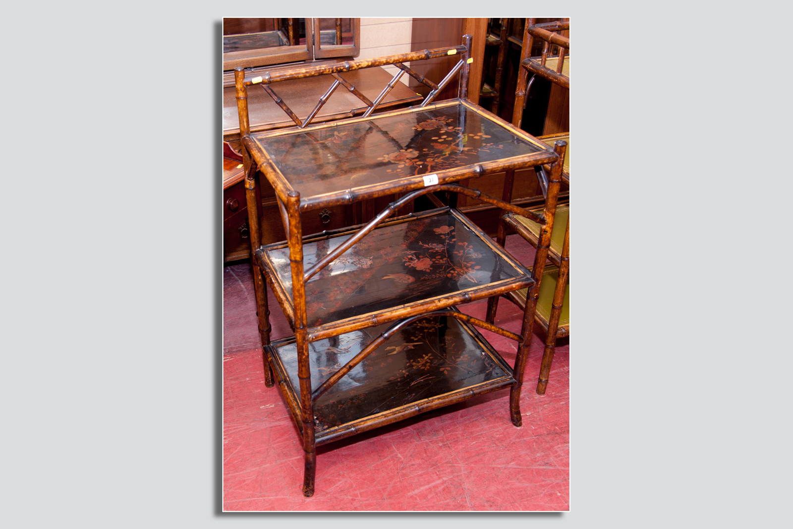 A bamboo and lacquerwork three shelf stand, all three shelves decorated with an overall pattern of