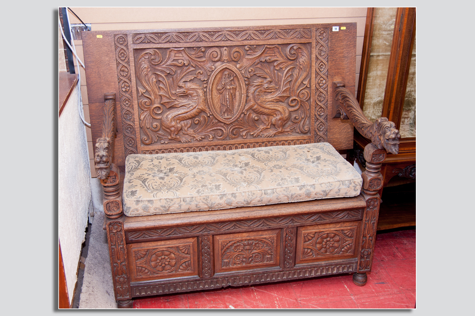 A late 19th/early 20th Century heavily carved settle, the back having an oval carved religious