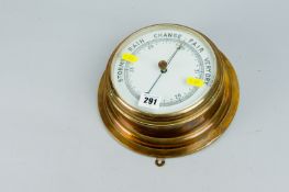 A brass encased ship`s type barometer, 9 ins (23 cms) overall diameter