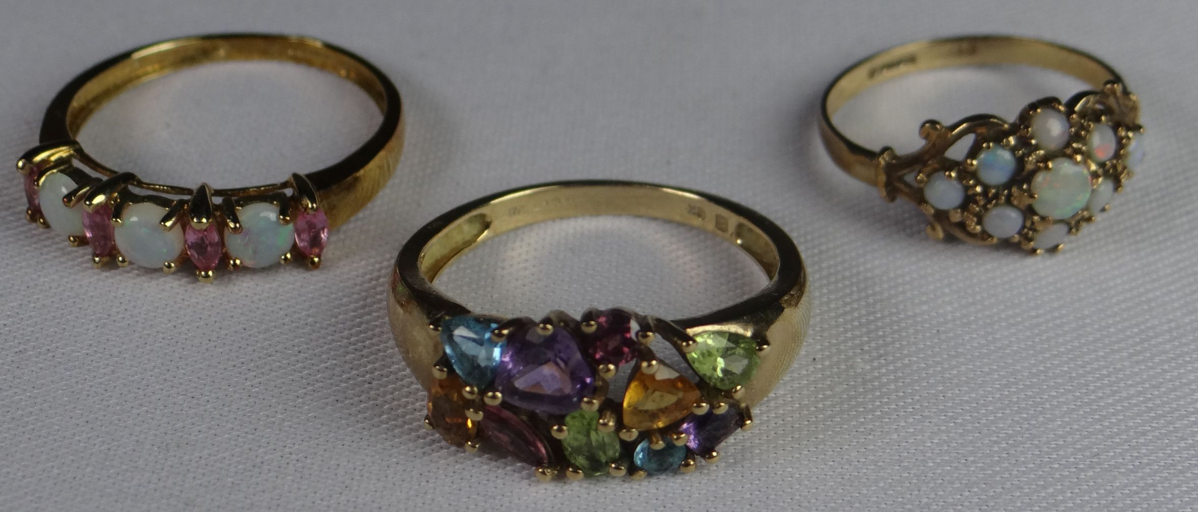 Three modern 9ct yellow gold rings with small opals / coloured stones, 7.3gms