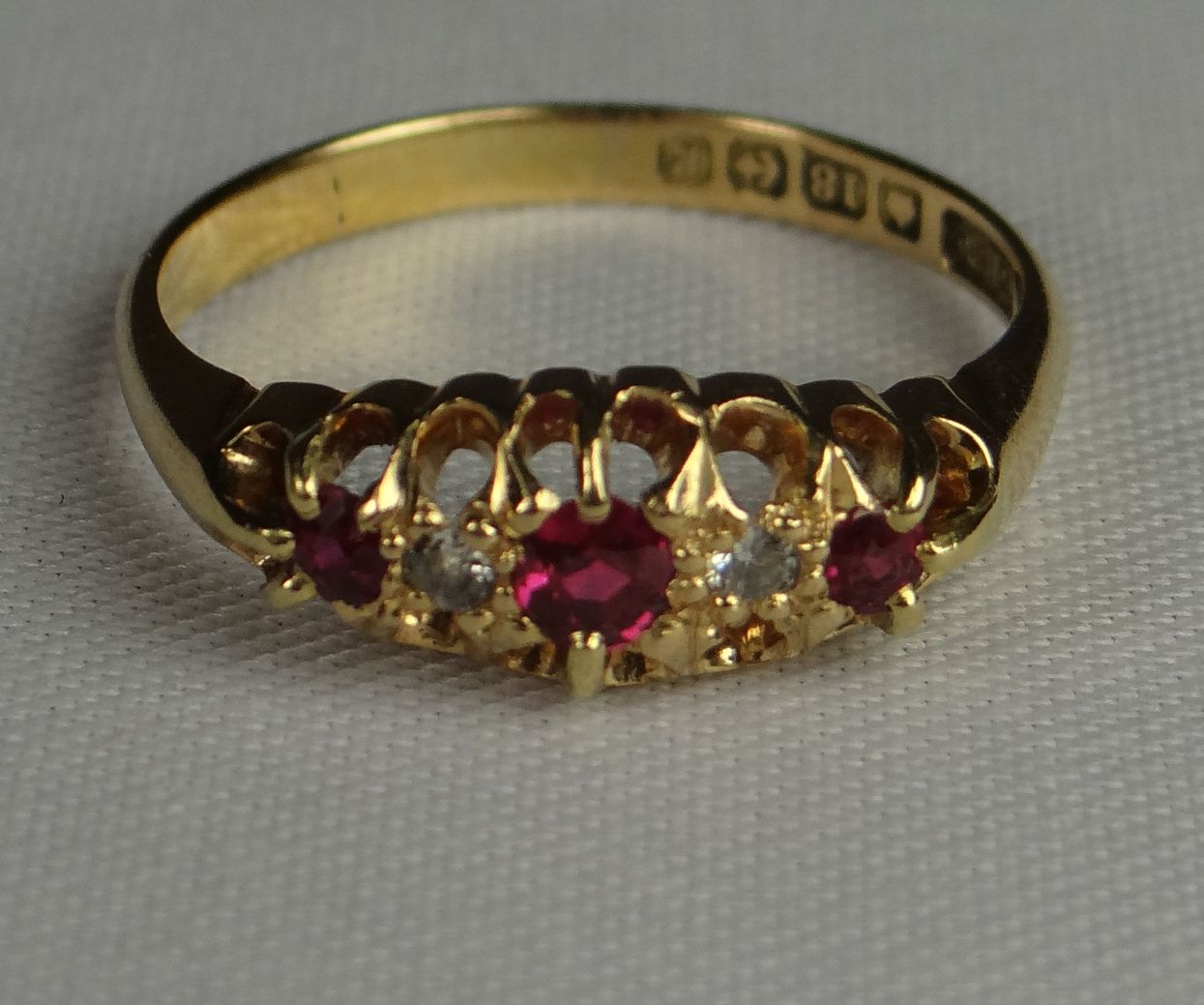 An 18ct yellow gold ring with three rubies interspersed with diamonds, 3.7gms