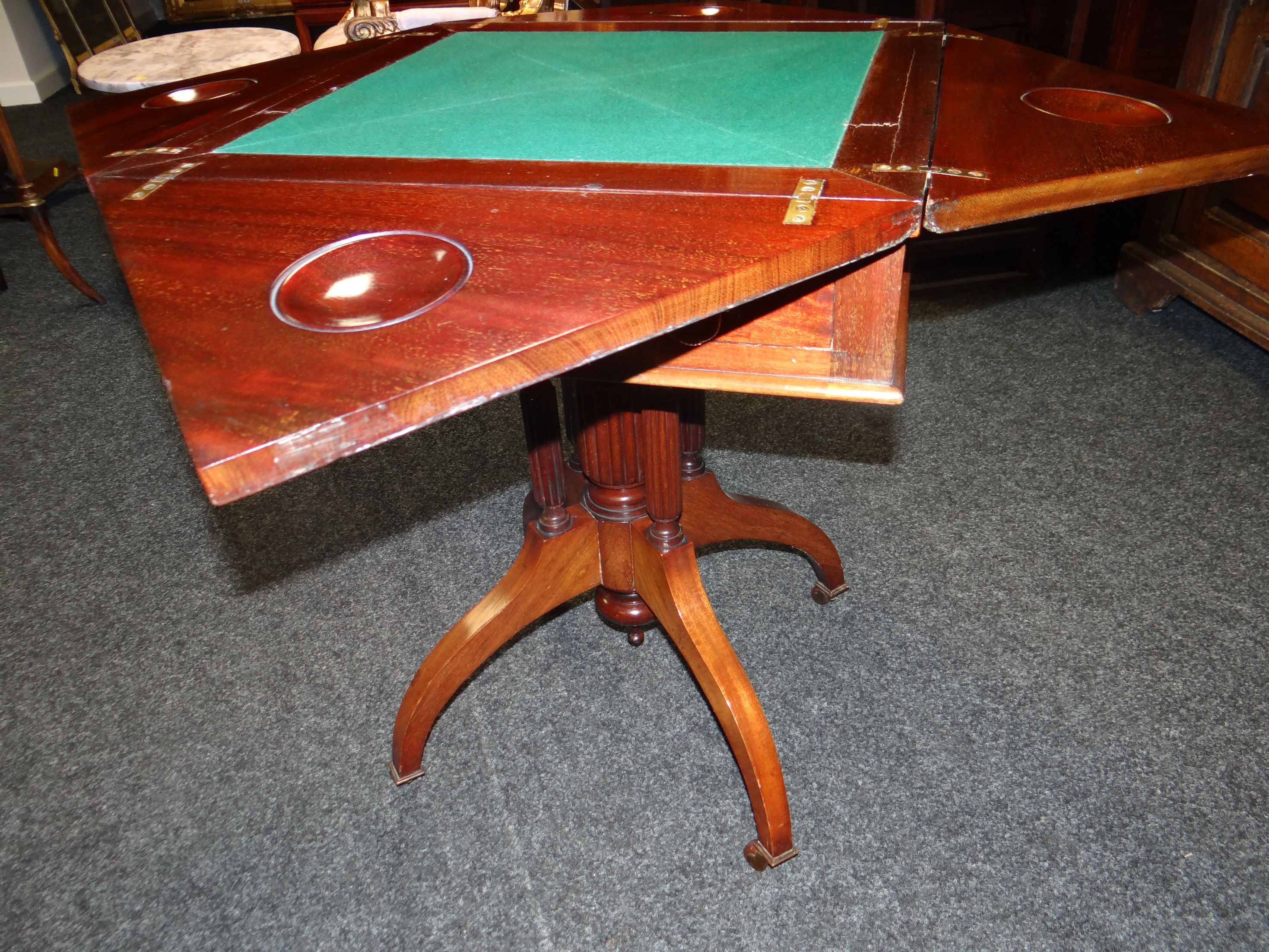 An Edwardian mahogany envelope-style games table, having a baize-lined interior, single drawer