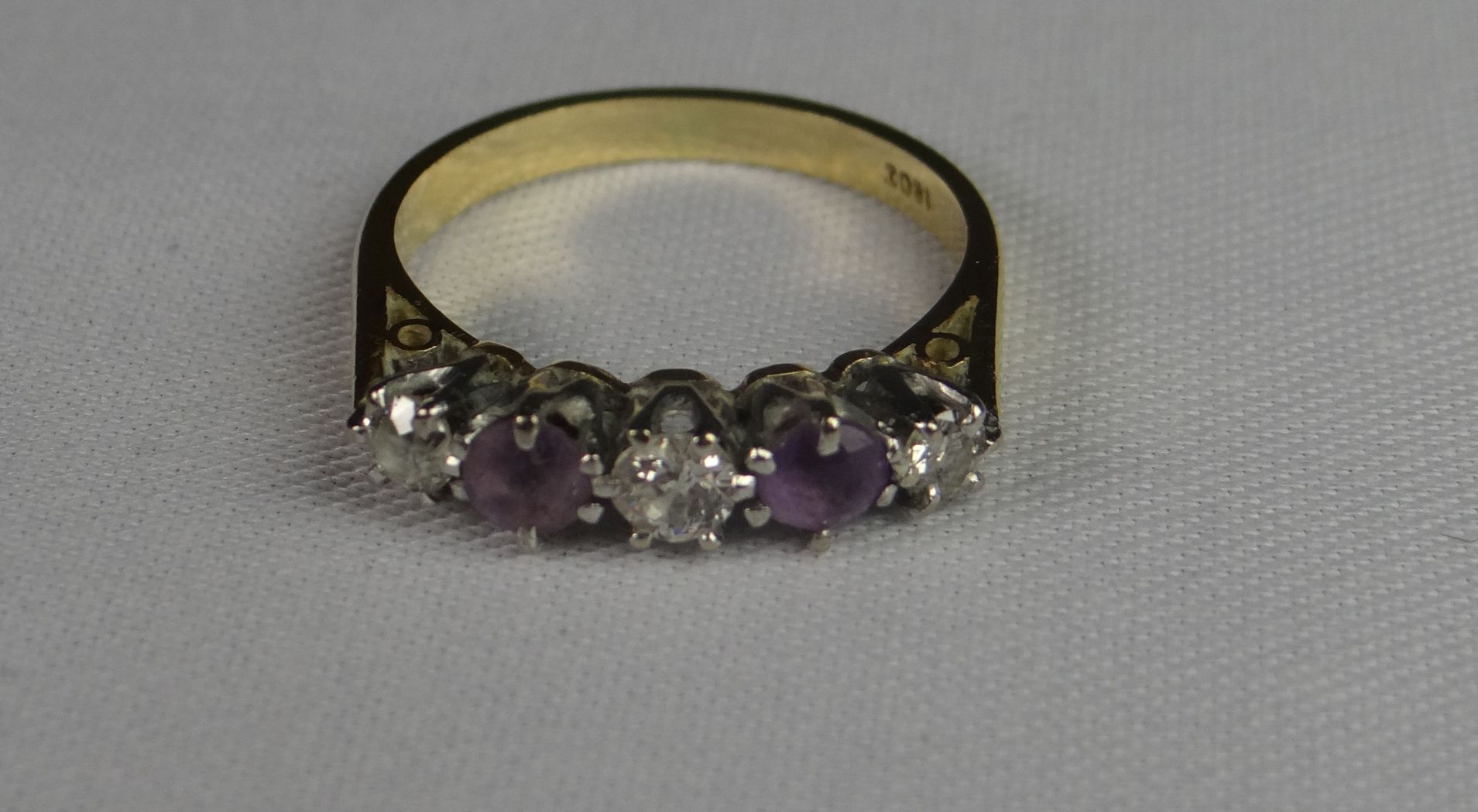 An 18ct yellow gold ring with three small diamonds and two amethysts