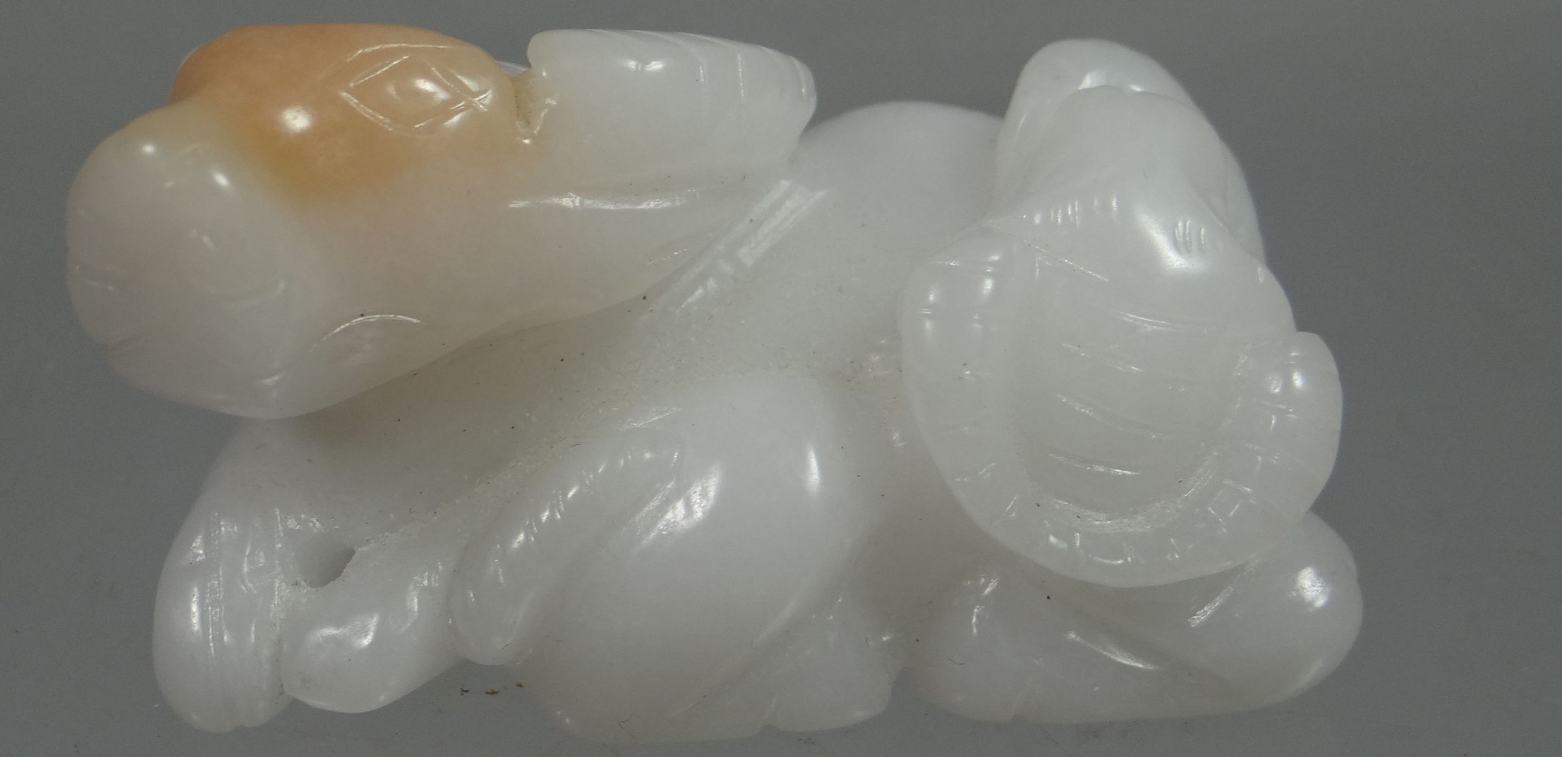 A carved white jade reclining bison, 5.5cms long