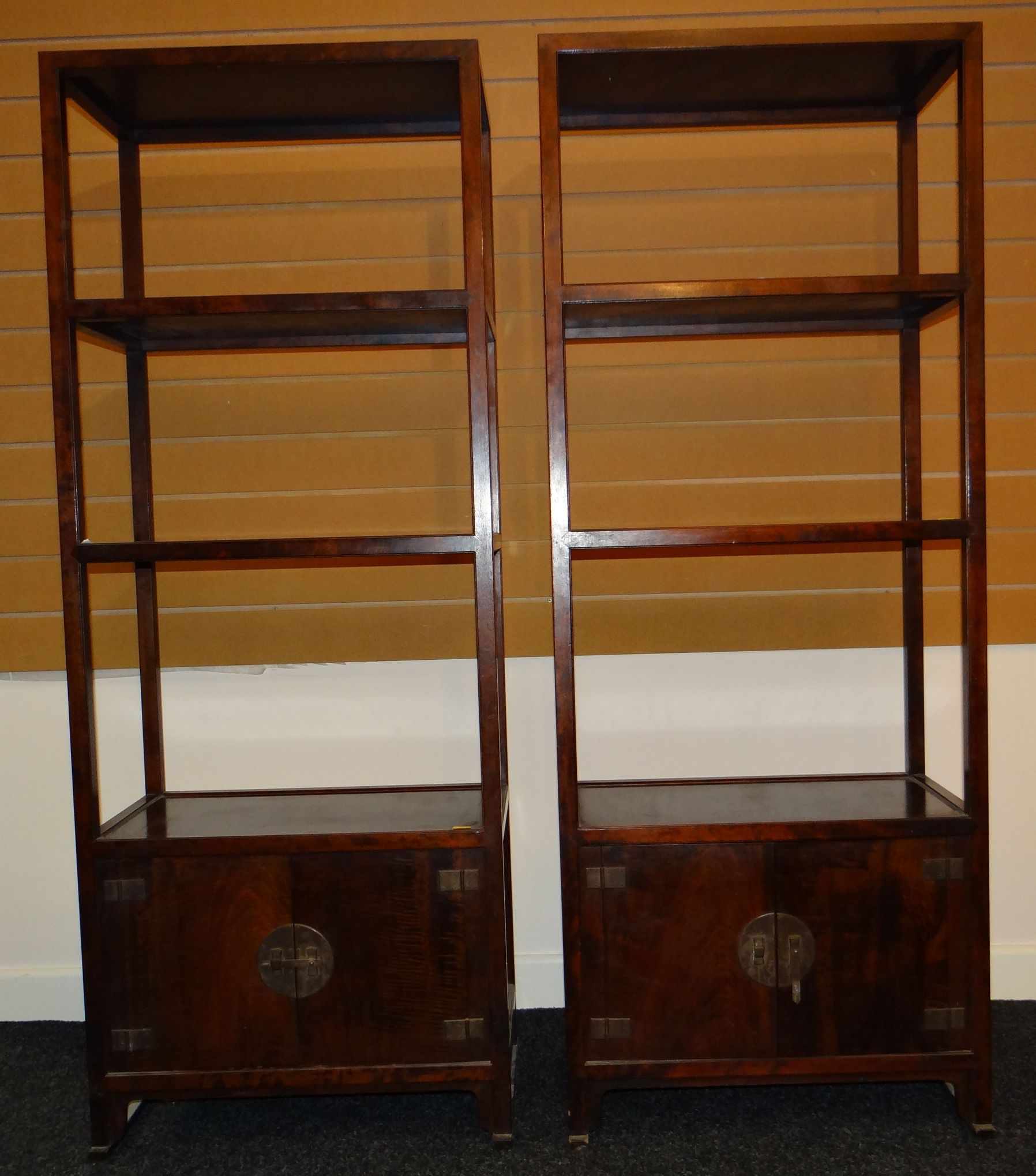 A pair of Chinese hardwood narrow open book cases with base cupboards, height 60ins (152cms)