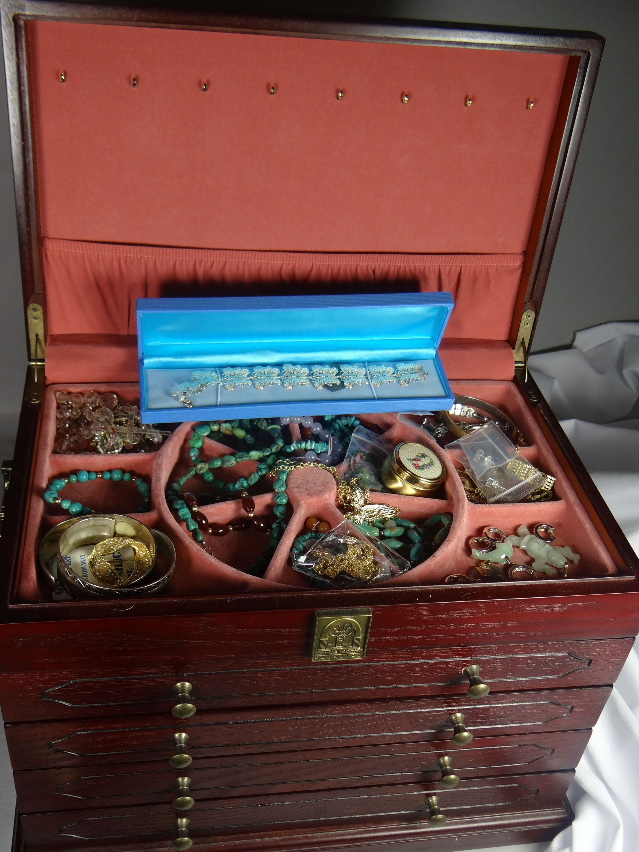 A modern four drawer jewellery box with mixed contents including silver items