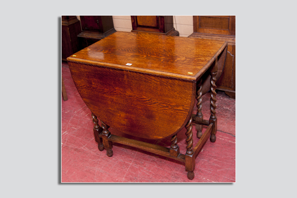 A 1930s drop leaf oak dining table with barley twist supports and oblong stretchers