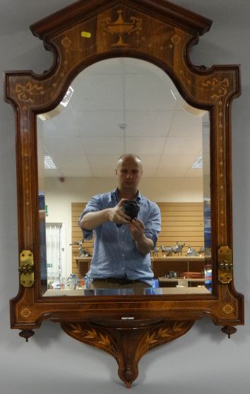 An inlaid and marquetry rosewood framed wall mirror of shaped bevelled-glass, the frame of