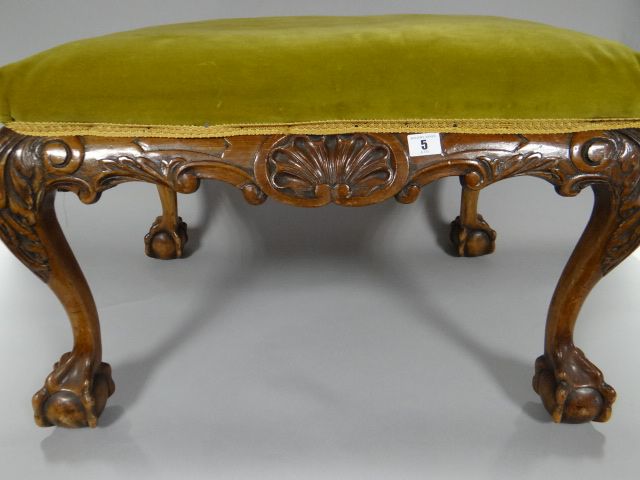 A mahogany cushion-top stool, heavily carved all-round and on ball and claw supports, 26 x 19ins (