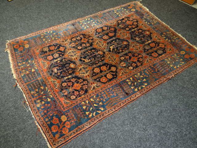 A good antique Persian rust coloured wool carpet, typically decorated with exotic floral border and