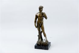 A finely sculpted hollow bronze figurine of a standing nude male figurine on a naturalistic base and