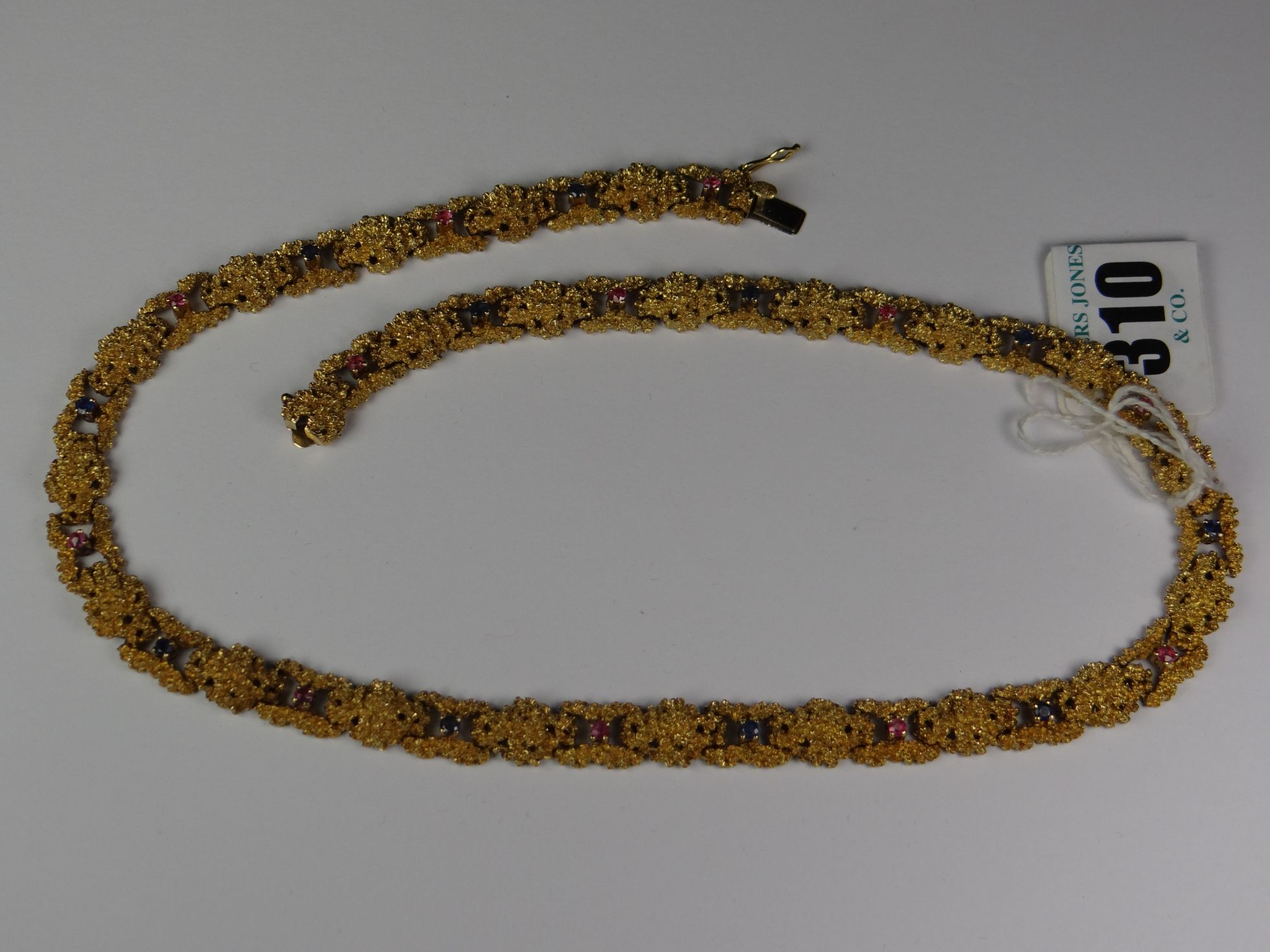 An unmarked but assumed 18ct yellow crusty-gold link necklace set with rubies and sapphires, 76gms
