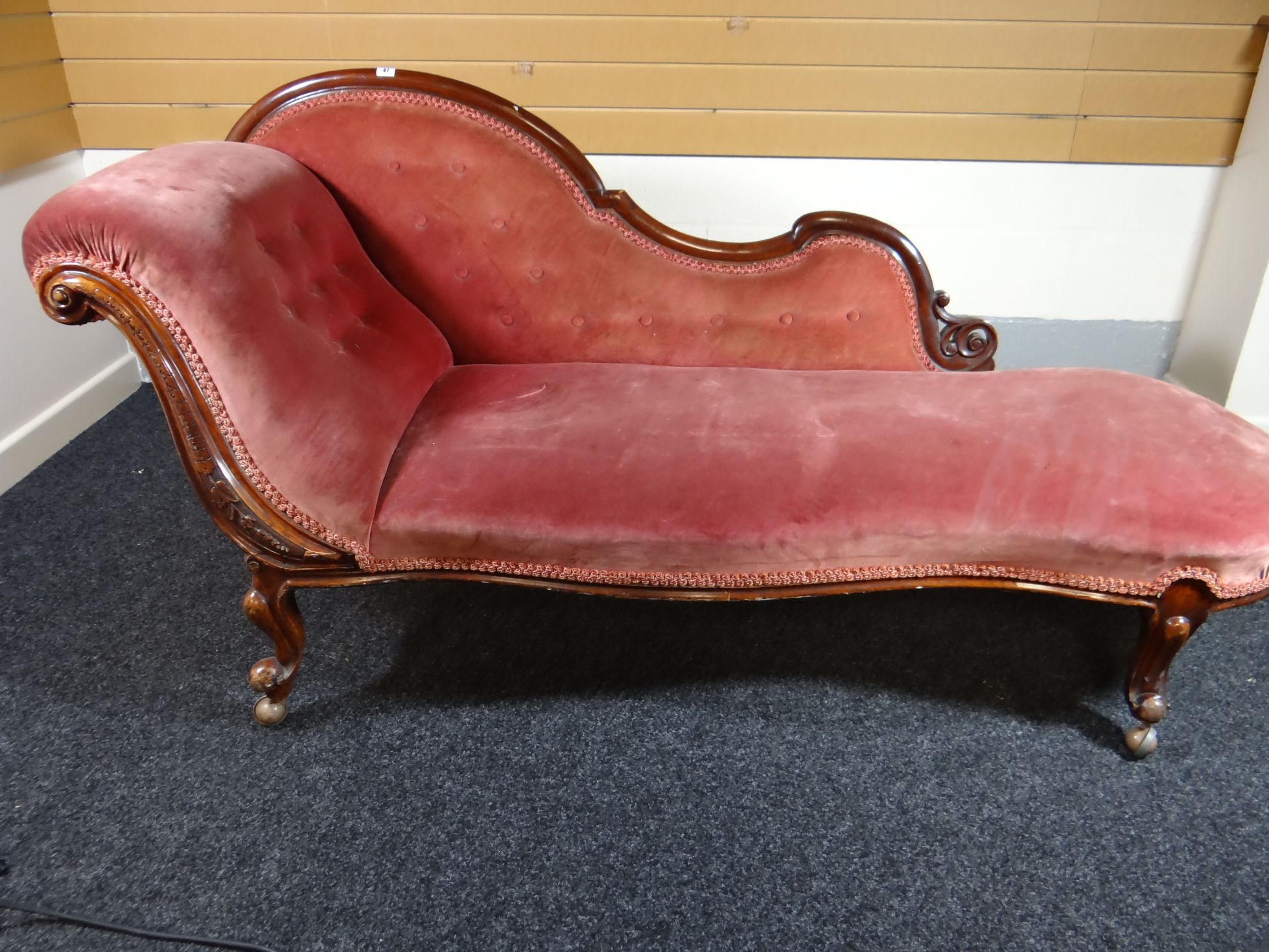 A Victorian mahogany chaise-longue of shapely form, with carved front support and in pink