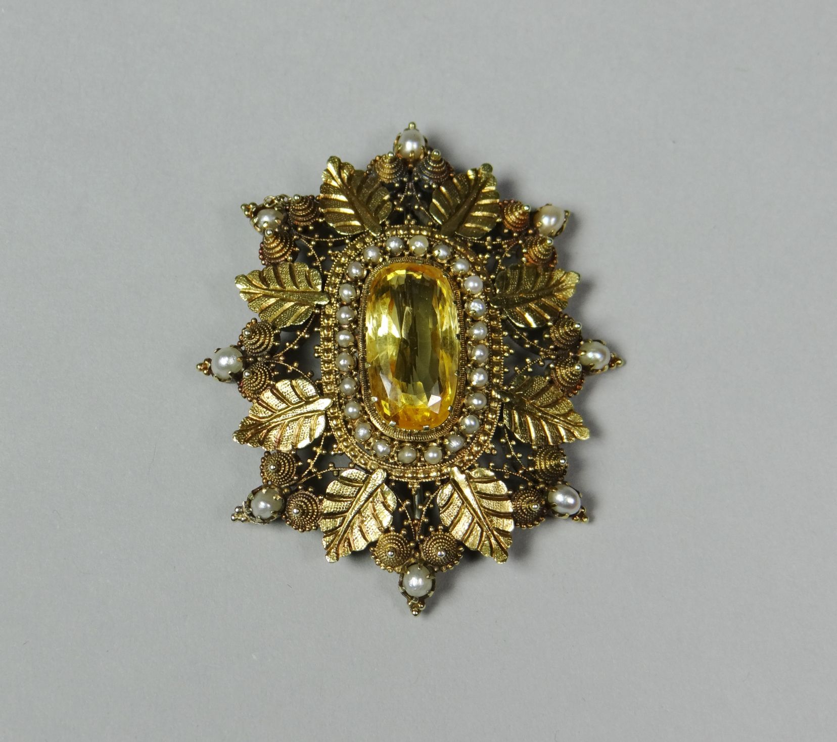 A fine quality yellow gold oval brooch of leaf and fruit design centred with a large oval yellow