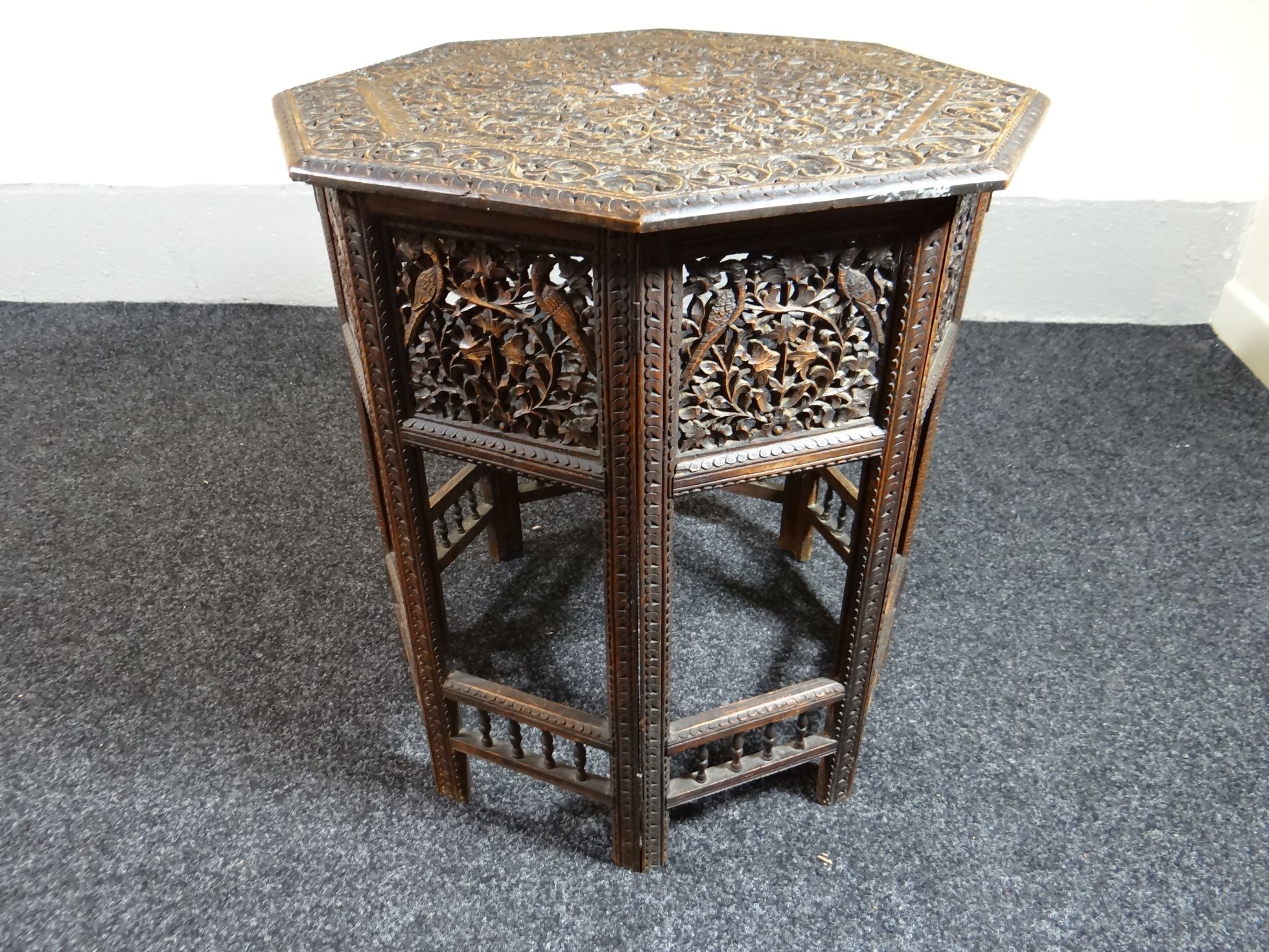 An Indian octagonal carved and pierce-work table, the top profusely carved with foliage and the