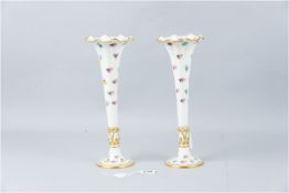 A pair of Minton china white ground floral decorated trumpet vases on circular bases with tapered