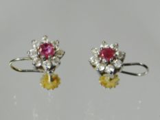 A pair of ruby and diamond floral design earrings with central ruby surrounded by tiny diamonds