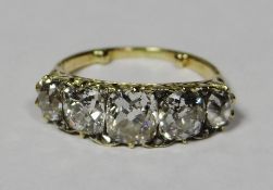An unmarked yellow gold ring set with five graduated cushion cut diamonds, centre stone visual