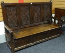 An eighteenth Welsh oak box-seat settle, the back having four carved floral panels, 63ins wide x