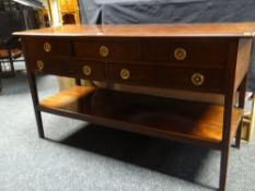 A mahogany five drawer dresser-base with lower plank shelf, on reeded and tapered corner-supports,