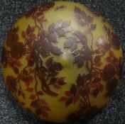 A shallow-dome shaped amber glass ceiling light shade having raised ochre coloured foliage and