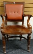 An heavy mahogany desk chair having a padded back with shaped arms and turned front supports on