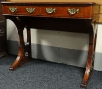 A mahogany console table with two drawers having brass handles and on an ecclesiastical-style