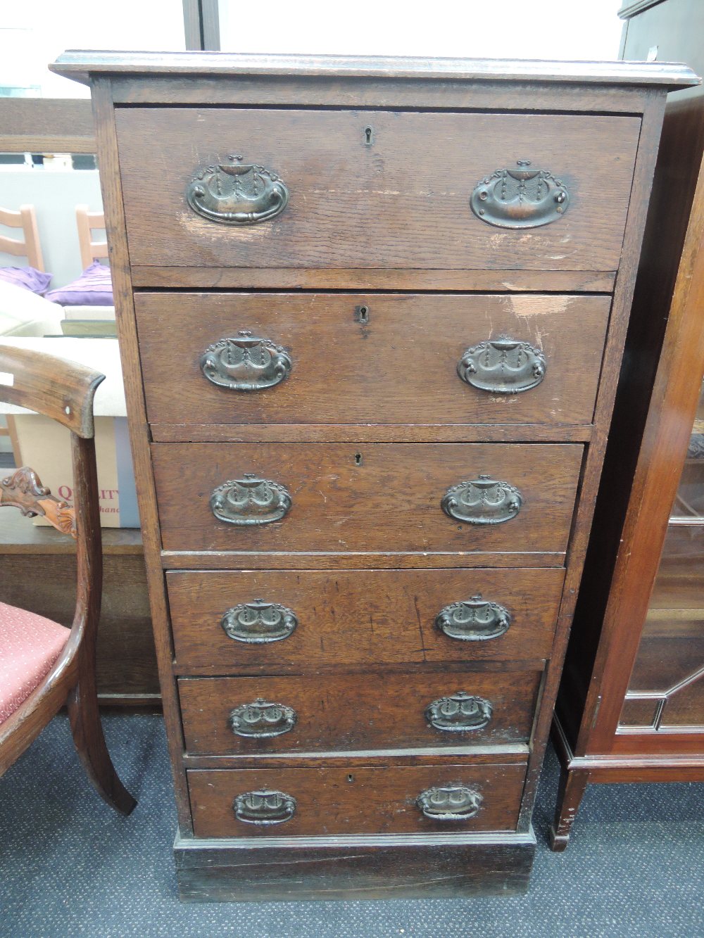 A late 19th century oak chest of six short drawers, having ornate handles on plinth base