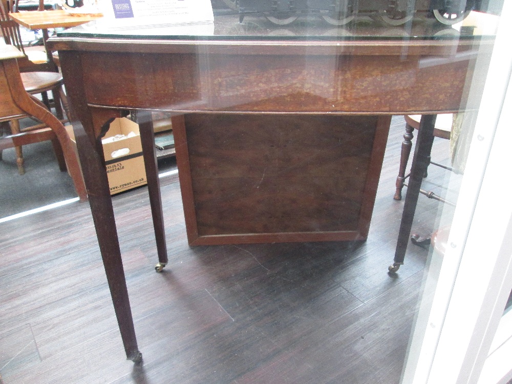 An Edwardian mahogany side table, having glass top, with square tapered legs on brass casters