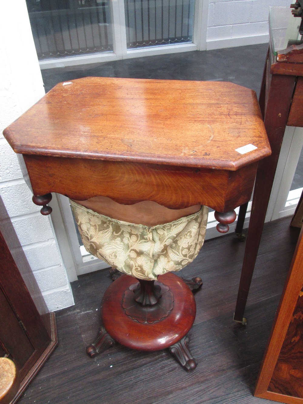 A George IV mahogany sewing table having lift top, scallop undertier, carved column on quad foliate