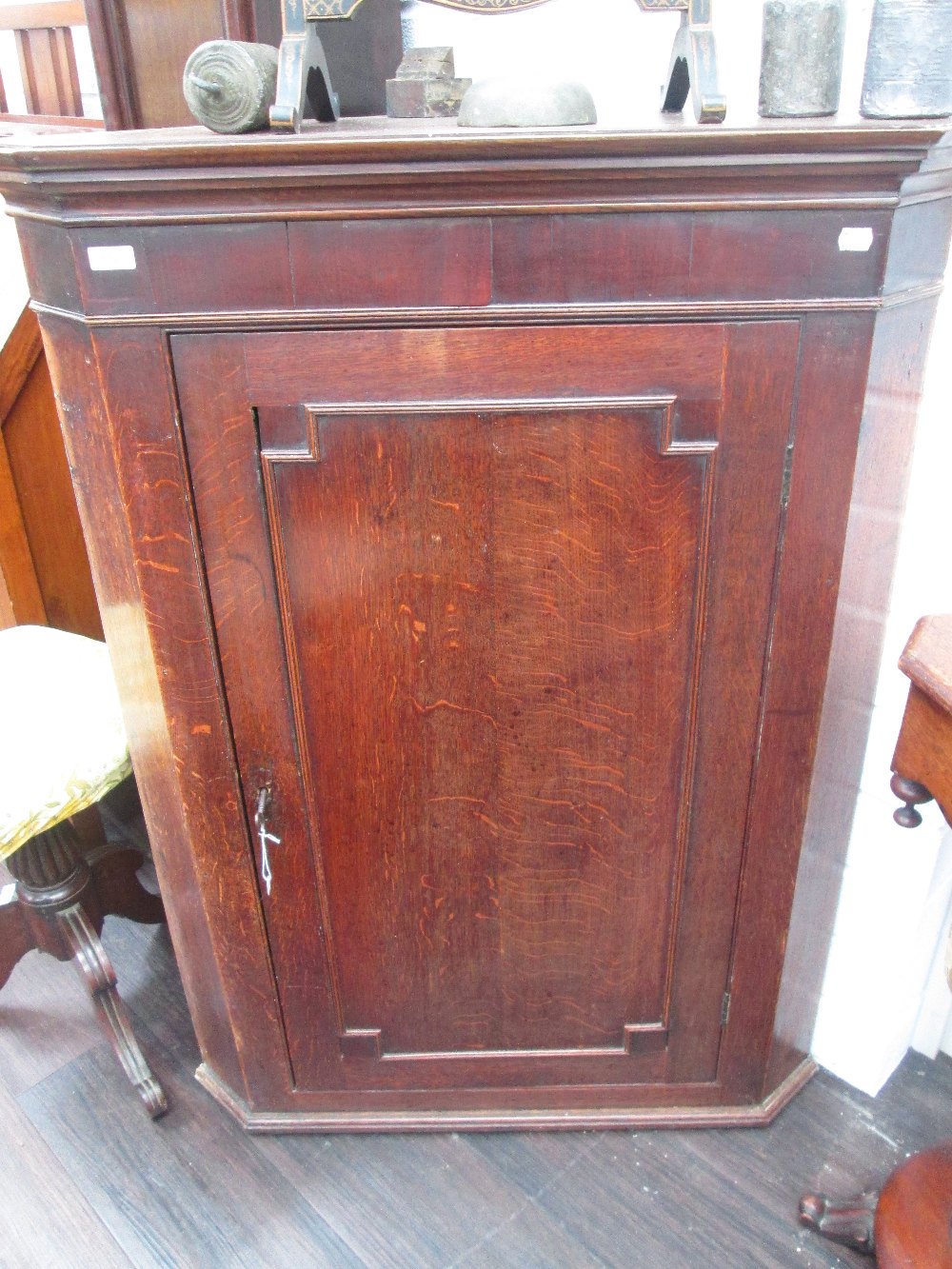 An early 20th century mahogany corner cupboard, having plinth top and base and panel decoration