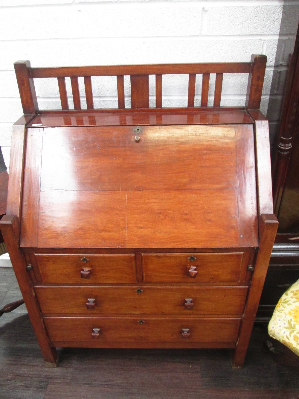 An early 20th century mahogany bureau in the Arts & Crafts style having slatted superstructure over